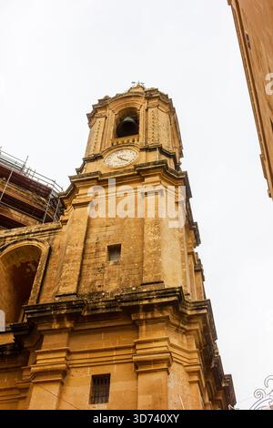 Storica Torre dell'Orologio di Malta: Facciata in pietra dorata, torre campanaria alta con esterno intemprato Foto Stock