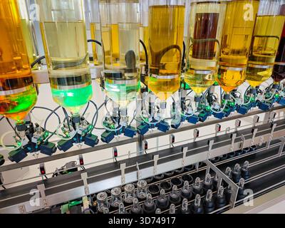 Produzione di profumi. Profumi diversi in bottiglia. Linea di produzione robotizzata di profumi con erogazione automatica di fragranze Foto Stock