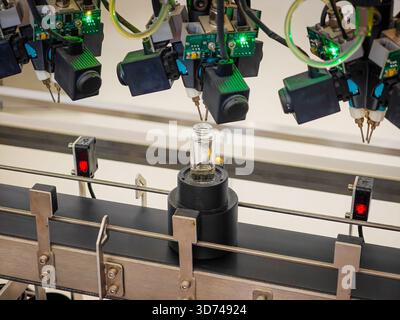 Produzione di profumi. Profumi diversi in bottiglia. Linea di produzione robotizzata di profumi con erogazione automatica di fragranze Foto Stock