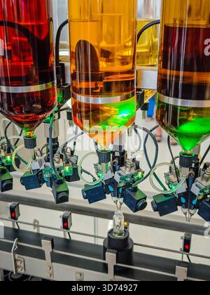 Produzione di profumi. Profumi diversi in bottiglia. Linea di produzione robotizzata di profumi con erogazione automatica di fragranze Foto Stock