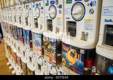Vista ravvicinata di una fila di distributori automatici di gachapon per ricevere le capsule gacha con giocattoli all'interno di una sala giochi ad Asakusa, Tokyo, Giappone Foto Stock
