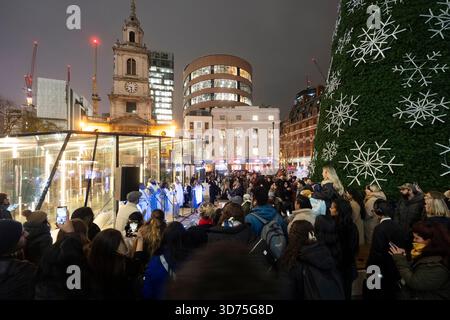 Un coro canta al One Bishopsgate Plaza di Londra, durante un festoso evento di illuminazione degli alberi di Natale. Foto Stock