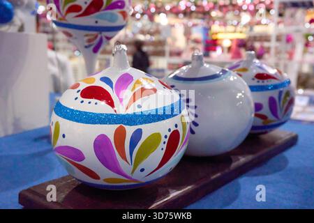 Tre ornamenti di vetro splendidamente decorati si trovano su un tavolo di legno, ognuno con un design unico e colorato. Messico, Puebla, Chignahuapan, decorativo CH Foto Stock