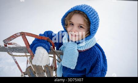 Bambini con slitta in un campo innevato invernale. Momenti di divertimento invernale con bambini e slitte vintage in legno. Biglietto d'auguri invernale. Divertimento invernale per i bambini con vintage sle Foto Stock