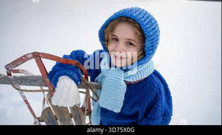 Bambini con slitta in un campo innevato invernale. Momenti di divertimento invernale con bambini e slitte vintage in legno. Biglietto d'auguri invernale. Divertimento invernale per i bambini con vintage sle Foto Stock