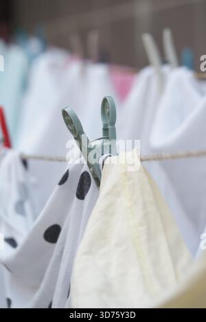 Clothespin che tiene il tessuto bagnato su una clothesline al sole Foto Stock