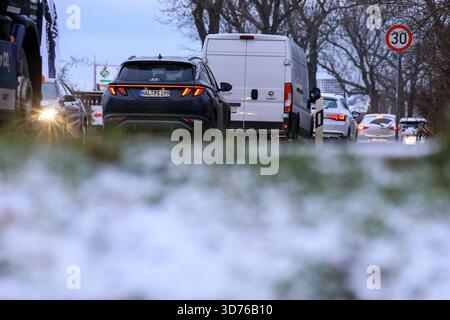 Lipsia, Germania. 24 novembre 2025. Le auto si accumulano su una strada arteria nella parte occidentale di Lipsia dopo la nevicata di notte. Secondo il servizio meteorologico tedesco, un sistema a bassa pressione sta portando in Germania un'ondata di aria leggera dell'Atlantico. La neve non rimarrà, invece il tempo sarà instabile, freddo e umido. Crediti: Jan Woitas/dpa/Alamy Live News Foto Stock