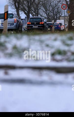 Lipsia, Germania. 24 novembre 2025. Le auto si accumulano su una strada arteria nella parte occidentale di Lipsia dopo la nevicata di notte. Secondo il servizio meteorologico tedesco, un sistema a bassa pressione sta portando in Germania un'ondata di aria leggera dell'Atlantico. La neve non rimarrà, invece il tempo sarà instabile, freddo e umido. Crediti: Jan Woitas/dpa/Alamy Live News Foto Stock