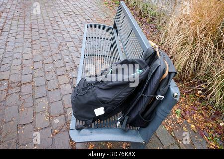 Due zaini neri su una panchina pubblica Foto Stock
