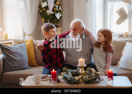 Bambini che trascorrono il Natale con il nonno anziano a casa. Foto Stock