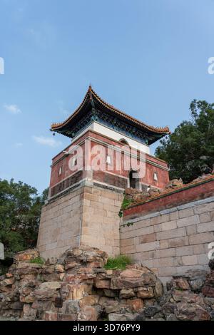 Una tradizionale torre cinese con un tetto ornato e' costruita su un massiccio e rustico fondamento in pietra. Lo scatto ad angolo basso sottolinea l'altezza a della struttura Foto Stock