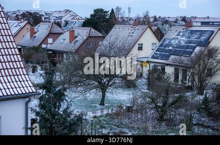 Lipsia, Germania. 24 novembre 2025. Diversi edifici residenziali in una proprietà residenziale sono coperti di neve e un grande impianto fotovoltaico può essere visto su uno dei tetti. Crediti: Jan Woitas/dpa/Alamy Live News Foto Stock