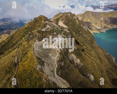 Vista aerea delle aspre creste di montagna che gettano ombre sulle acque turchesi, un arazzo di texture e tonalità, il lago Quilotoa, la provincia di Cotopaxi, l'Ecuad Foto Stock