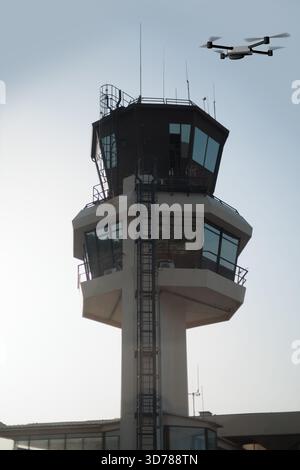 Drone che vola sopra la torre di controllo dell'aeroporto in una giornata di sole Foto Stock