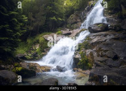 Le acque cristalline scorrono aggraziatamente su terreni rocciosi alla cascata Molieres, Vall d'Aran, Catalogna Foto Stock