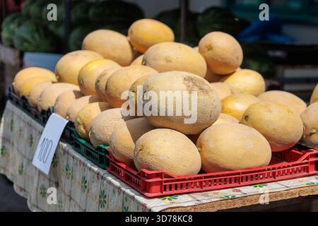 Esposizione di meloni freschi in un mercato locale alla luce del sole, che mostra prodotti stagionali per gli acquirenti Foto Stock