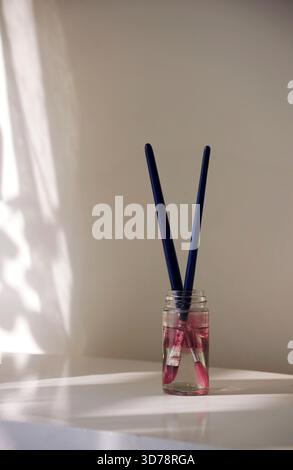 Pennelli con vernici rosa in un vaso di vetro Foto Stock