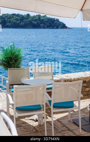Rilassanti posti a sedere sul mare vicino alle calme acque blu in una giornata di sole in un idilliaco ambiente costiero Foto Stock