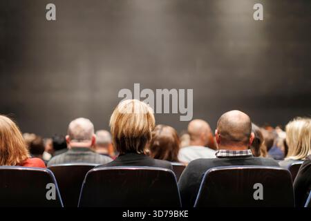 Membri del pubblico seduti in anticipo prima di uno spettacolo in un grande teatro Foto Stock
