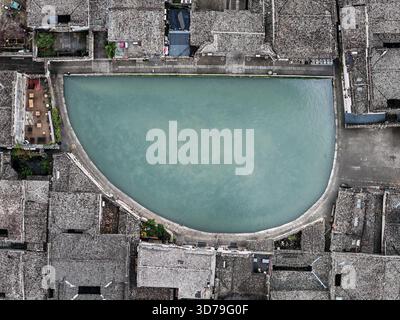 Vista aerea del tranquillo laghetto Half Moon, annidato tra antiche abitazioni con tetti di piastrelle grigie, che creano una scena tranquilla, il villaggio di Hongcun, Anhui, CH Foto Stock