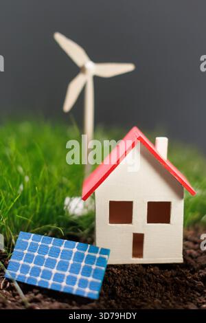 Casa in miniatura circondata da fonti di energia rinnovabili Foto Stock