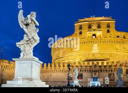 Statue di angeli illuminate di notte sul Ponte Sant'Angelo, con sullo sfondo Castel Sant'Angelo. Roma, Italia. Foto Stock