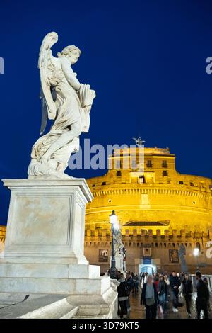 Statue di angeli illuminate di notte sul Ponte Sant'Angelo, con sullo sfondo Castel Sant'Angelo. Roma, Italia. Foto Stock