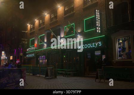McCooley's Irish bar nel quartiere Cavern di Liverpool di notte. L'entrata è illuminata da una luce verde neon brillante. Foto Stock