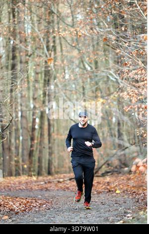 Uomo che corre nella foresta autunnale Foto Stock