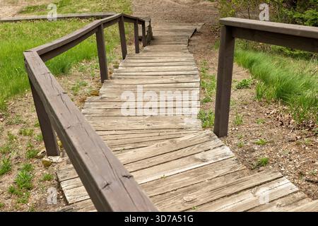 Scale in legno e corrimano che conducono verso il basso alla spiaggia di un lago. Foto Stock