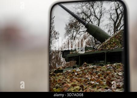 Riflesso di un veicolo militare corazzato mimetizzato con un cannone montato rivolto verso il cielo visto in uno specchio laterale Foto Stock