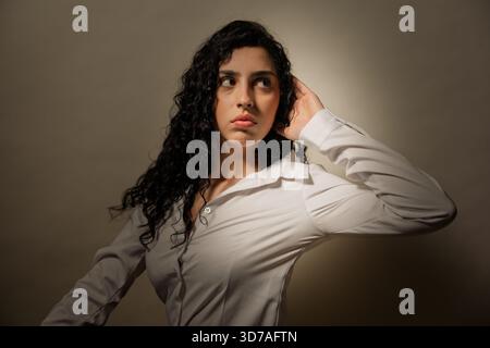 Giovane donna che si concentra, ascolta notizie o pettegolezzi con un'espressione attenta Foto Stock