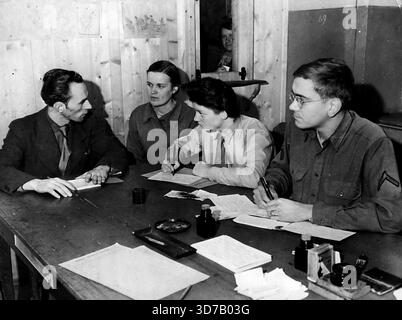 Primo passo verso la Road Home -- Peter Olinikow, un interprete francese, intervista Heleno Smakowa, un ucraino, uno dei tanti sfollati a Camp St. Jacques, Knutango, Francia, mentre Jacqueline Drigout del corpo ausiliario delle donne francesi registra le informazioni in francese e privato Samuel H, Booker di Louisville, Kentucky, in inglese. Questi registri aiuteranno a organizzare il ritorno dei rifugiati nelle loro terre d'origine. La maggior parte delle persone in questo particolare campo sono di nazionalità russa. Nei cinque campi di sfollati di Hayange in Francia, circa 2.000 persone, forme Foto Stock
