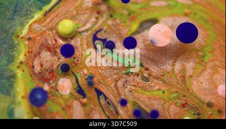 Flusso di vernice. Inchiostro brillante. Bolla d'acqua colorata blu, giallo e verde sfocata che galleggia su uno sfondo acrilico astratto e creativo. Foto Stock