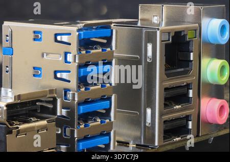 Primo piano di un pannello posteriore in metallo dotato di porte USB sovrapposte, RJ 45 e prese audio con codifica a colori Foto Stock