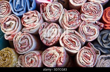 Rotoli di tessuto organizzati con vari motivi e tessuti colorati, ideali per cuciture, moda e concetti artigianali Foto Stock
