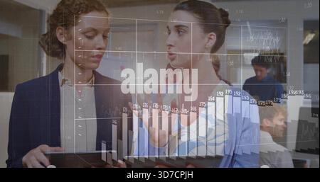 Analisi di due donne in abbigliamento da ufficio esame di grafici finanziari su tablet con sovrapposizione cartografica Foto Stock