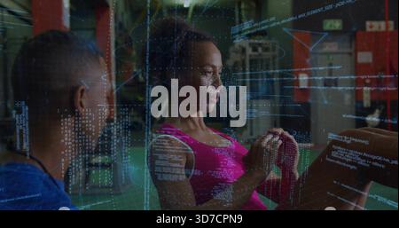 Donna con canotta rosa che tiene il nucleo in palestra, coach con camicia blu che guarda, codice sovrapposto Foto Stock