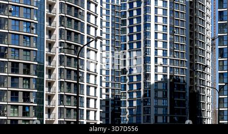 Architettura di moderni ed alti edifici di appartamenti con facciate di vetro e balconi. Torri residenziali urbane nello skyline della città che mostrano proprietà Foto Stock