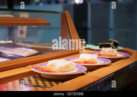 Piatti di sushi giapponesi su un nastro trasportatore di sushi all'interno di un ristorante di Tokyo Foto Stock
