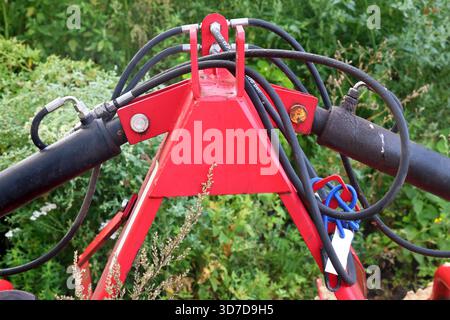Primo piano di macchine agricole rosse con tubi flessibili idraulici Foto Stock