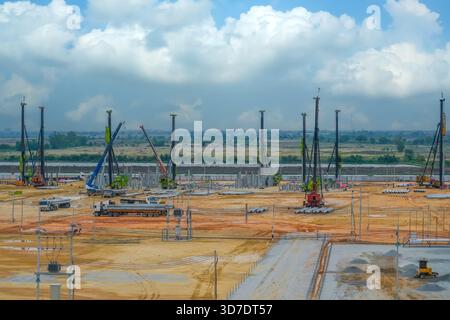 Un cantiere molto frequentato presenta diverse gru e macchinari che lavorano insieme a un progetto. Il cielo è parzialmente nuvoloso, e i macchinari sono situati acr Foto Stock