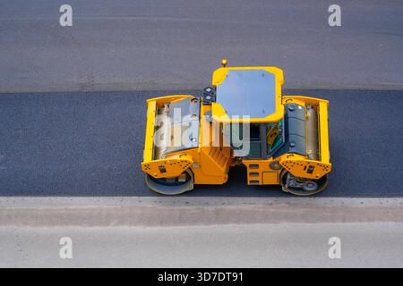Macchina a rulli gialli per riparazione stradale per asfalto, vista aerea. Foto Stock