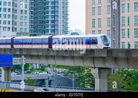 Il treno della metropolitana ad alta velocità e senza conducente attraversa lo skyline della città su un ponte di interscambio. Foto Stock