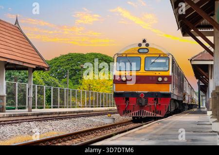 La locomotiva diesel arriva alla stazione passeggeri durante la corsa serale al tramonto. Foto Stock