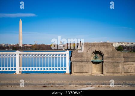 WASHINGTON DC - due fontane di pietra, con facce simili a pesci, adornano le alcove sull'Inlet Bridge presso il bacino delle maree, con il Monumento a Washington visibile oltre. Create dallo scultore greco Constantine Seferlis intorno al 1987, queste caratteristiche acquatiche uniche rendono omaggio a Manus “Jack” Fish, ex direttore regionale del National Park Service. Fish ha supervisionato grandi progetti come Constitution Gardens e il Vietnam Veterans Memorial. Le sculture fondono giocosamente le caratteristiche di Fish con un corpo simile a un pesce, facendo riferimento al suo nome e alla sua eredità. Sostituirono le fontane originali in bronzo precedentemente nelle alcove. Foto Stock