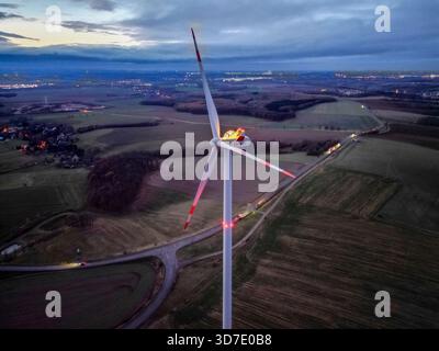 Lipsia, Germania. 24 novembre 2025. Steffen Flämig controlla l'illuminazione su un arco di candele sovradimensionato su una turbina eolica. L'arco di sei metri con il motivo Schwarzenberg splende a un'altezza di 140 metri sulla navicella della turbina eolica. Flämig ora vuole premere di nuovo il pulsante per il primo Avvento e accendere il suo arco di candela in alto sopra il Vorerzgebirge di notte. (Vista aerea con drone) credito: Jan Woitas/dpa/Alamy Live News Foto Stock