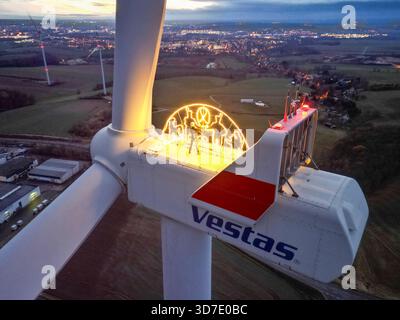 Lipsia, Germania. 24 novembre 2025. Steffen Flämig controlla l'illuminazione su un arco di candele sovradimensionato su una turbina eolica. L'arco di sei metri con il motivo Schwarzenberg splende a un'altezza di 140 metri sulla navicella della turbina eolica. Flämig ora vuole premere di nuovo il pulsante per il primo Avvento e accendere il suo arco di candela in alto sopra il Vorerzgebirge di notte. (Vista aerea con drone) credito: Jan Woitas/dpa/Alamy Live News Foto Stock