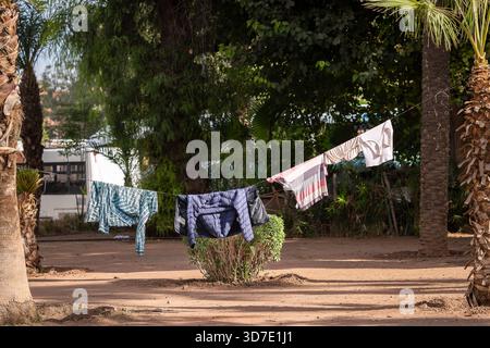 La lavanderia si asciuga in fila in un parco cittadino, Marrakech. Vestiti appesi su una linea di lavaggio in uno spazio verde cittadino per asciugare. Foto Stock