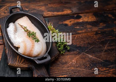 Filetto di merluzzo crudo incontaminato, in attesa di essere marinato e cucinato alla perfezione per una deliziosa esperienza culinaria. sfondo in legno. vista dall'alto. Foto Stock